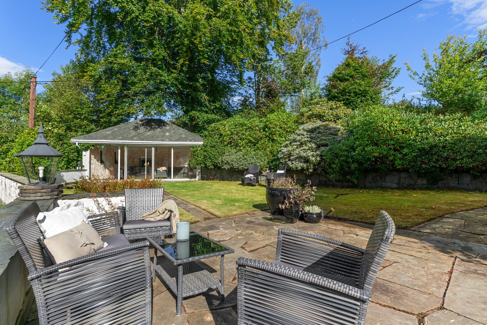 I enden av hagen er det et koselig lysthus med glasskyvedører og ildsted. Galleribilde