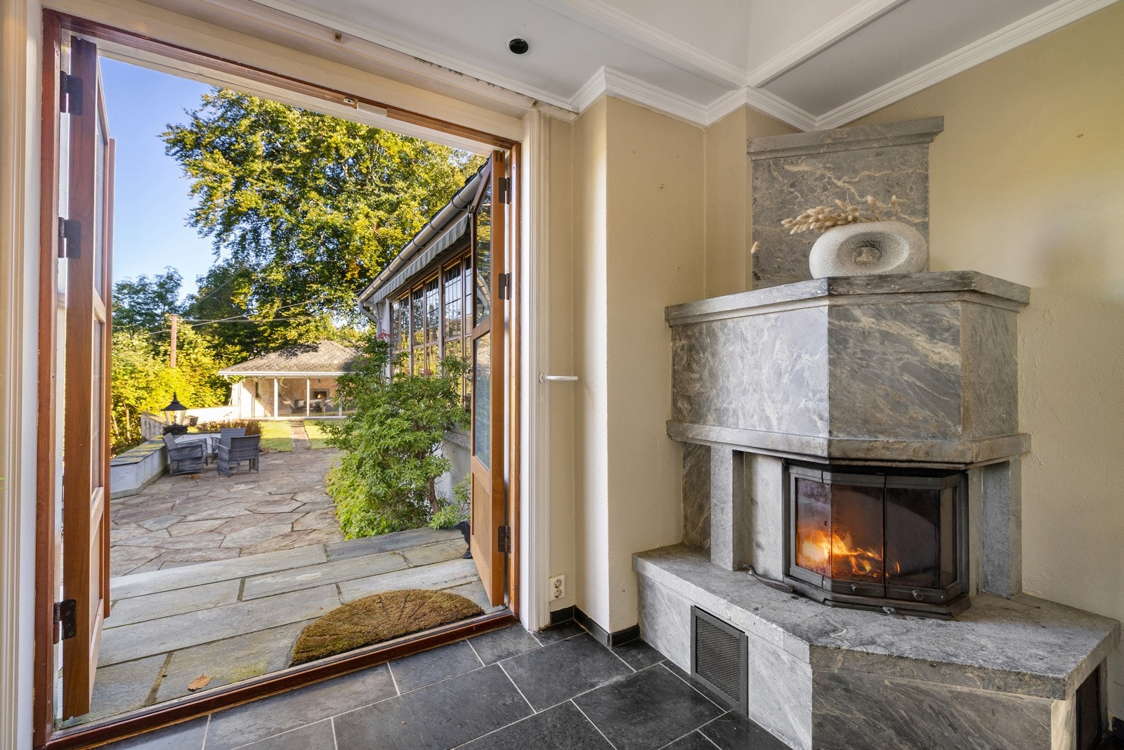 I sommerstuen er det flotte gulvfliser (varmekabel) og dobbelfløyet teakdør, som bringer deg ut i den vakre hagen. Galleribilde