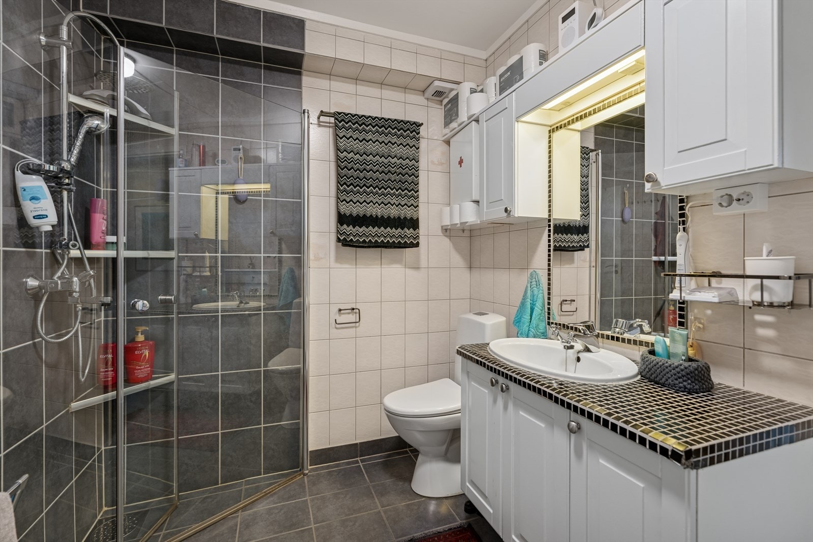 Baderommet er helfliset med en kombinasjon av grå og hvite fliser på gulv og vegger. I gulvet har man også varmekabler for ekstra komfort. Galleribilde