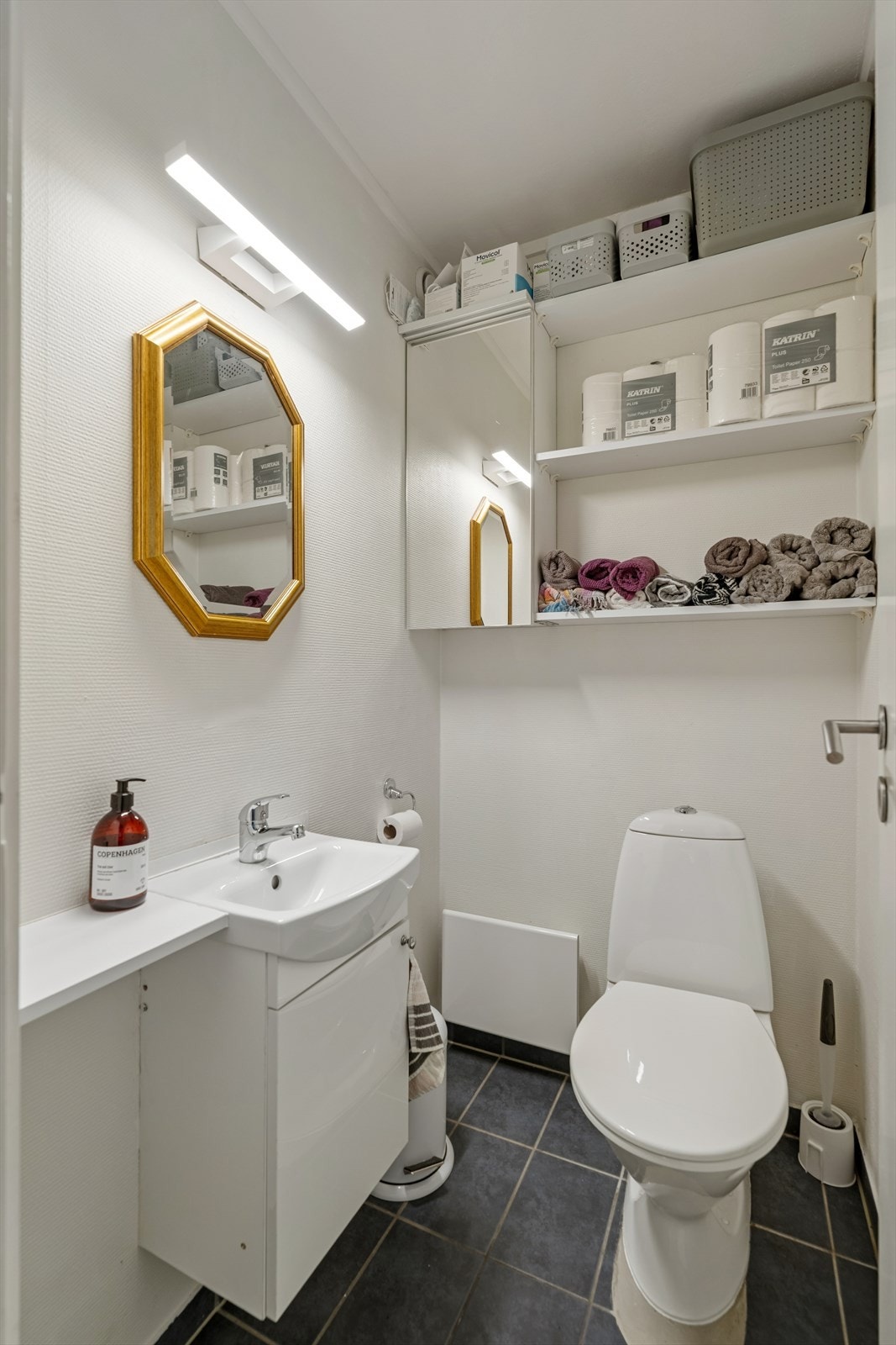Like ved baderommet finner man et ekstra toalettrom innredet med flislagt gulv og utstyrt med toalett, servant og hyller for ekstra lagringsplass. Galleribilde
