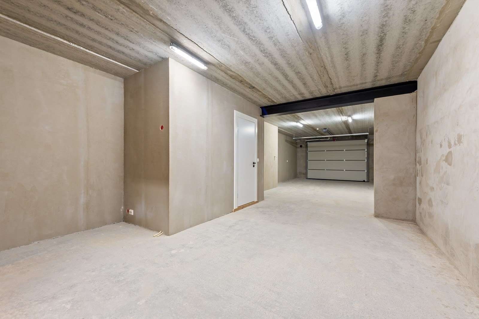 Garasje med plass til to biler. Det er tilrettelagt for elbil lader hvor trekkrør ligger klart fra garasje til sikringskap. Bildet er tatt under byggeprosessen. Galleribilde