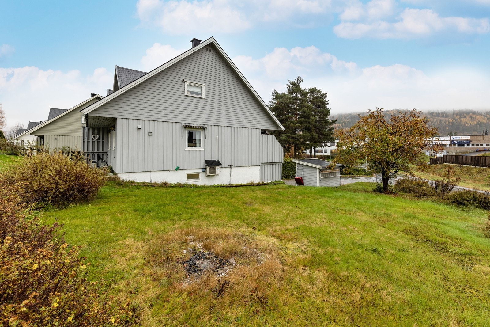 Opparbeidet hjørne tomt med gruset innkjørsel og beplantning. Galleribilde