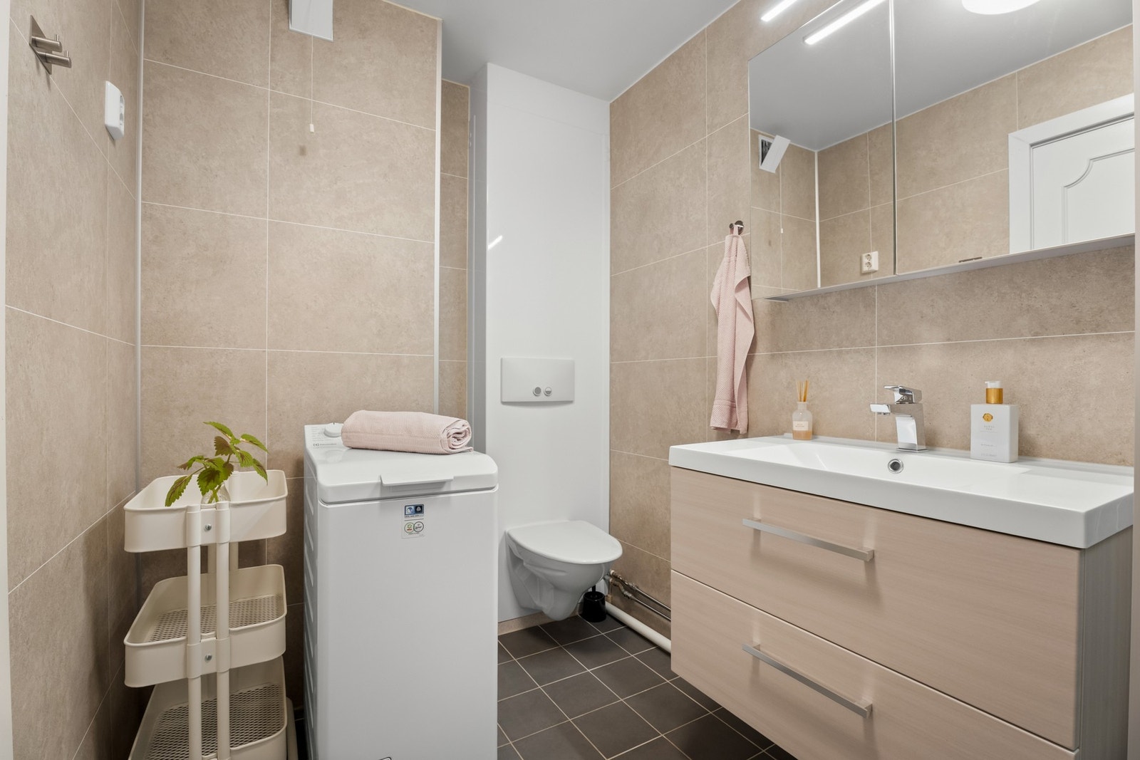 Innredning med skuffeseksjon med servant, speil og belysning på oveskap, dusjkabinett og vegghengt toalett Galleribilde