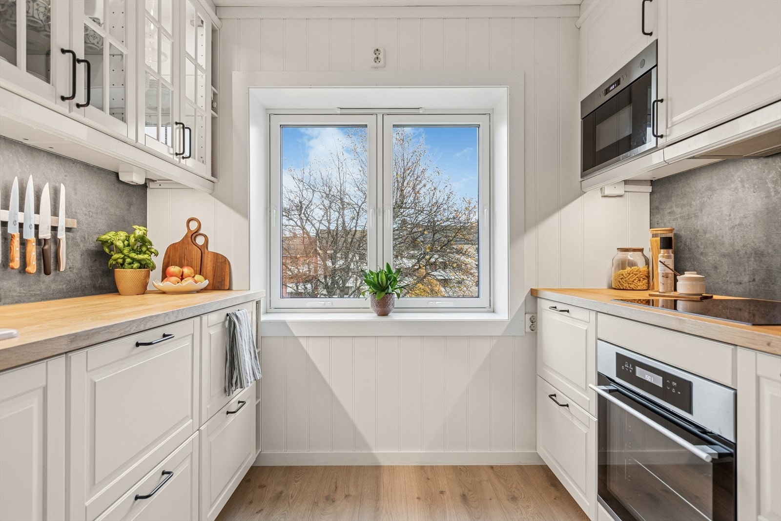 Kjøkkenet ble pusset opp i 2020 og har hvite, profilerte fronter og heltre benkeplate. Galleribilde