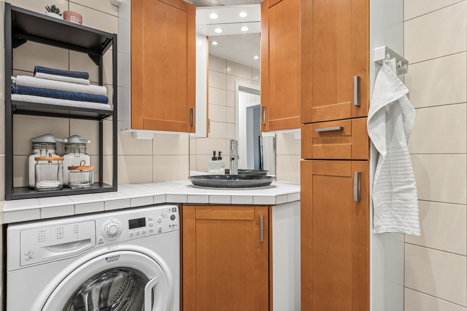 Badet har en raus innredning med nedfelt servant og opplegg for vaskemaskin. Galleribilde