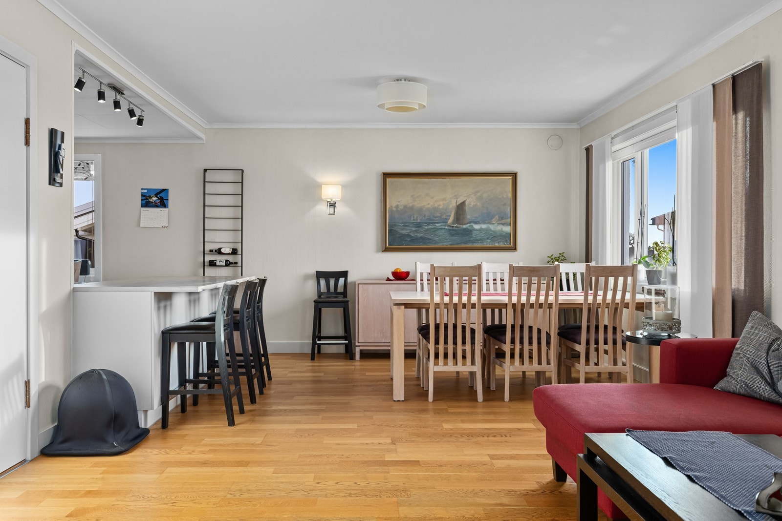 Stue har åpen løsning mot kjøkken, med stor kjøkkenøy som romdeler Galleribilde