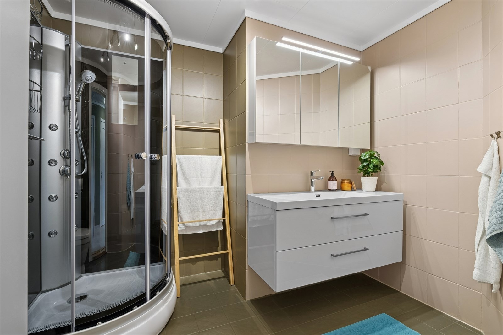 Baderommet har en pen skuffinnredning med lyssatt speilskap over, dusjkabinett fra 2021 og toalett. Galleribilde