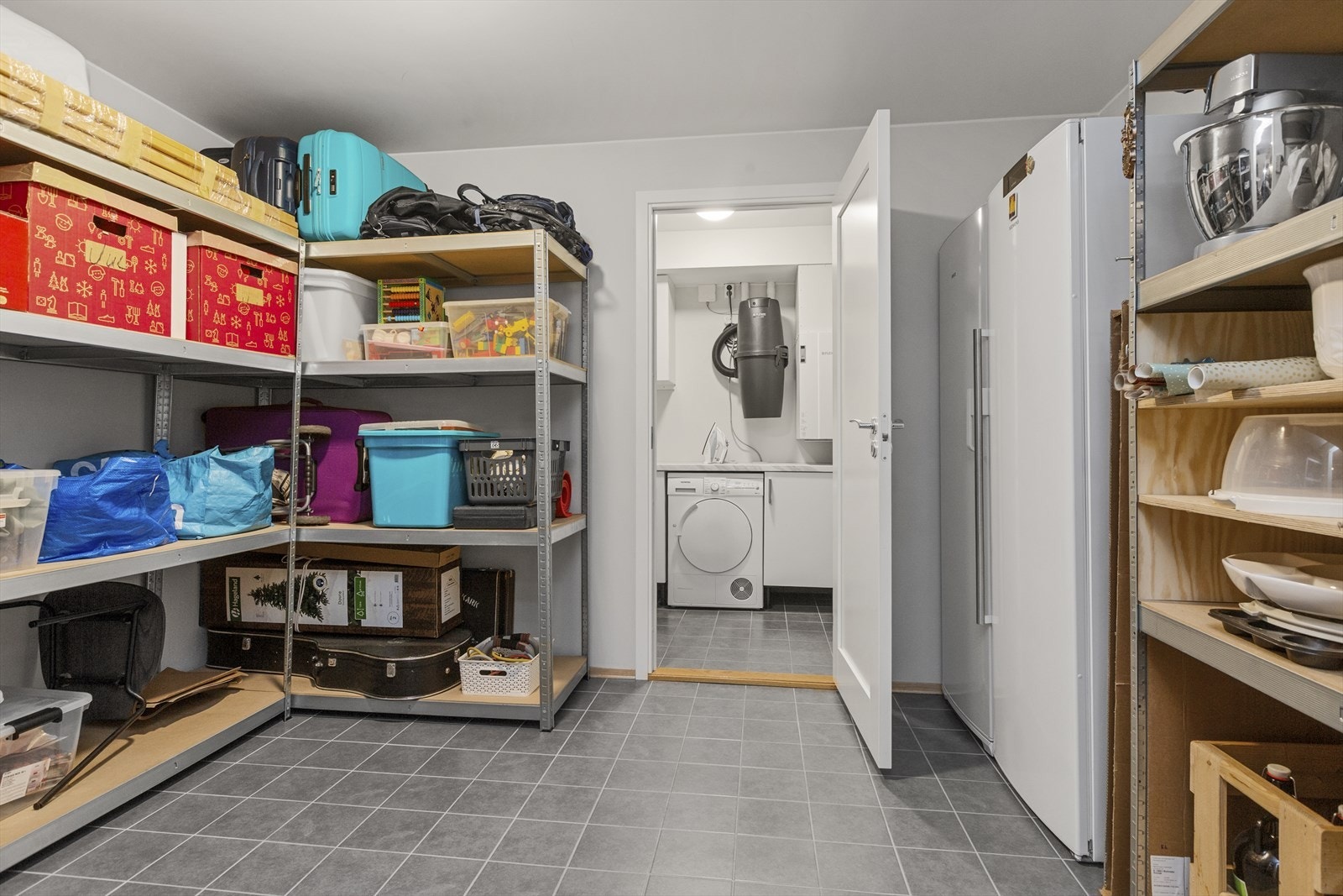 Vaskerommet er beliggende innforbi en romslig bod, begge med flislagt gulv og malte plater på vegger. Vaskerommet er utstyrt med slett innredning med benkeplate, utslagsvask og opplegg for vaskemaskin. Rommet er ikke godkjent, se mer pkt. ferdigattest. Galleribilde