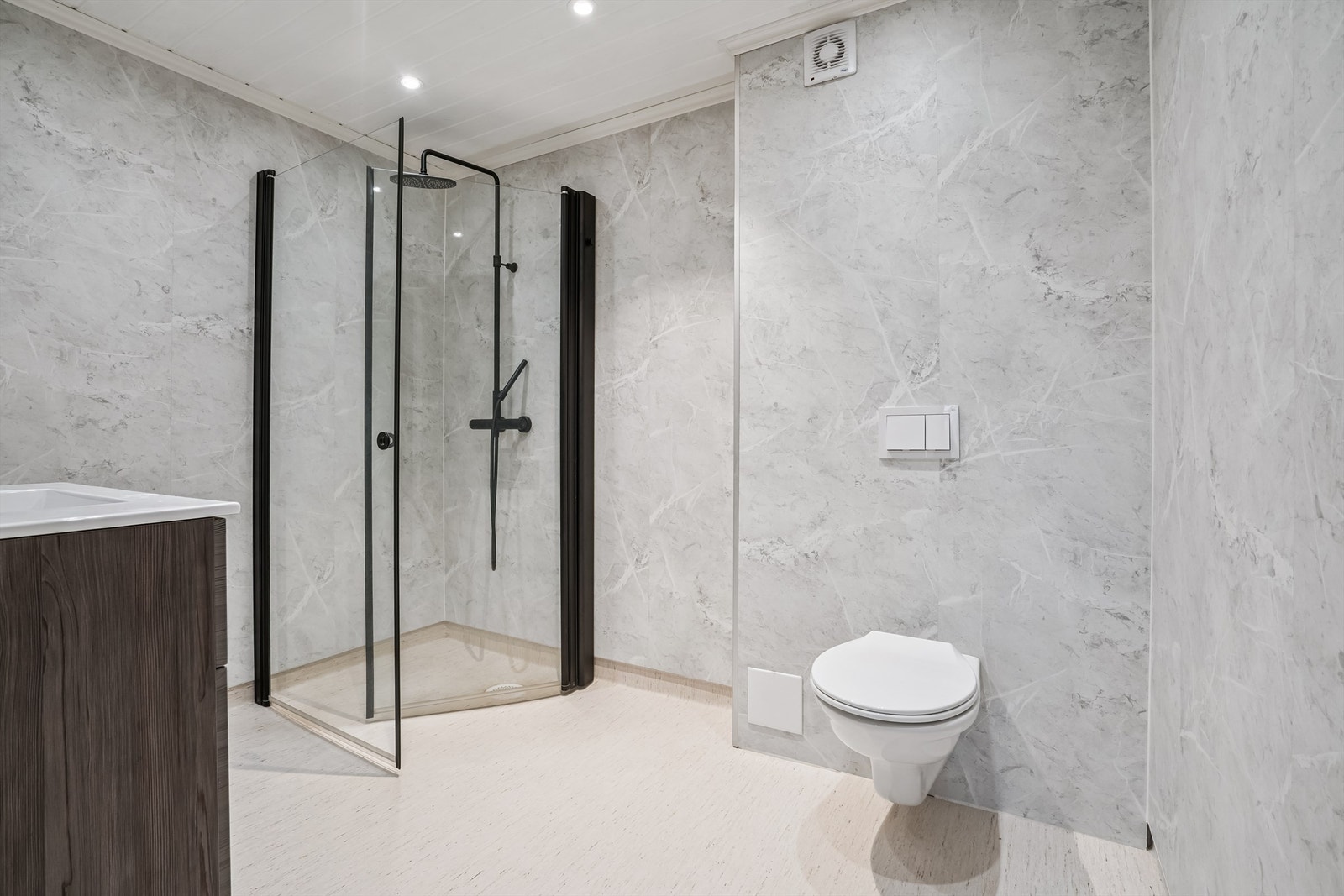 Her er det elektriske varmekabler i gulvet, vegghengt toalett og et praktisk dusjhjørne. Galleribilde