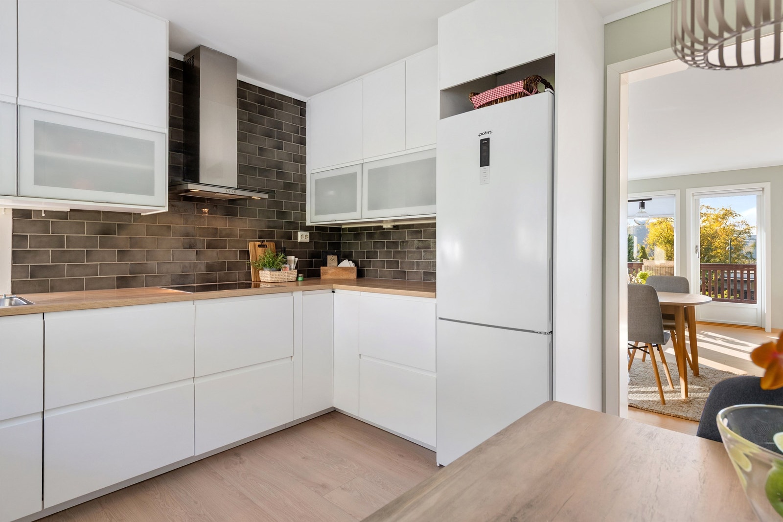 Kjøkkenet har integrert stekeovn, platetopp, mikrobølgeovn og oppvaskmaskin. Frittstående kjøleskap med fryser. Vegghengt ventilator. Det er lagt fliser mellom kjøkkenbenk og overskap. Galleribilde