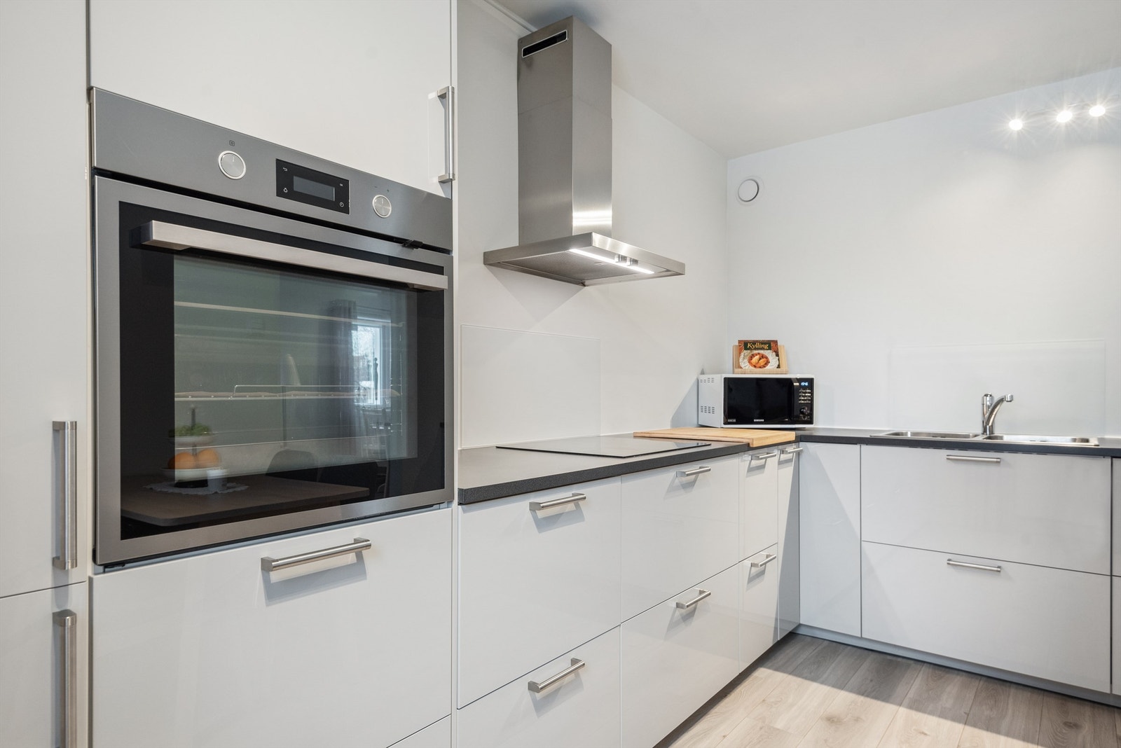 Kjøkkenventilator med kullfilter etablert over platetopp. Det er også etablert plater på veggflatene bak platetopp og vaskekum. Galleribilde