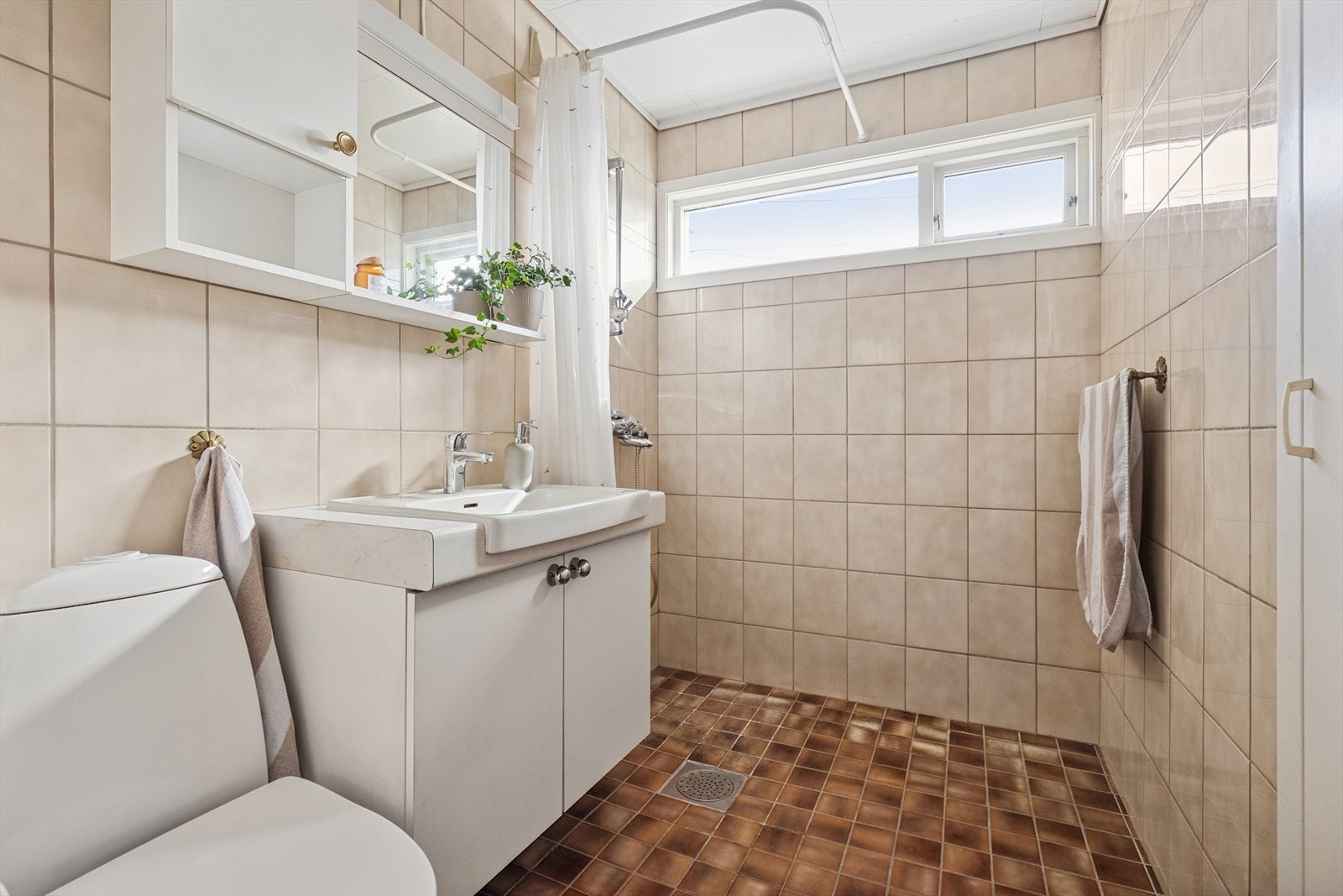Badet er av eldre standard fra 70-tallet og har gulvvarme samt innredning med servant, speil med lys, dusjhjørne, gulvstående toalett og plassbygget skap. Galleribilde