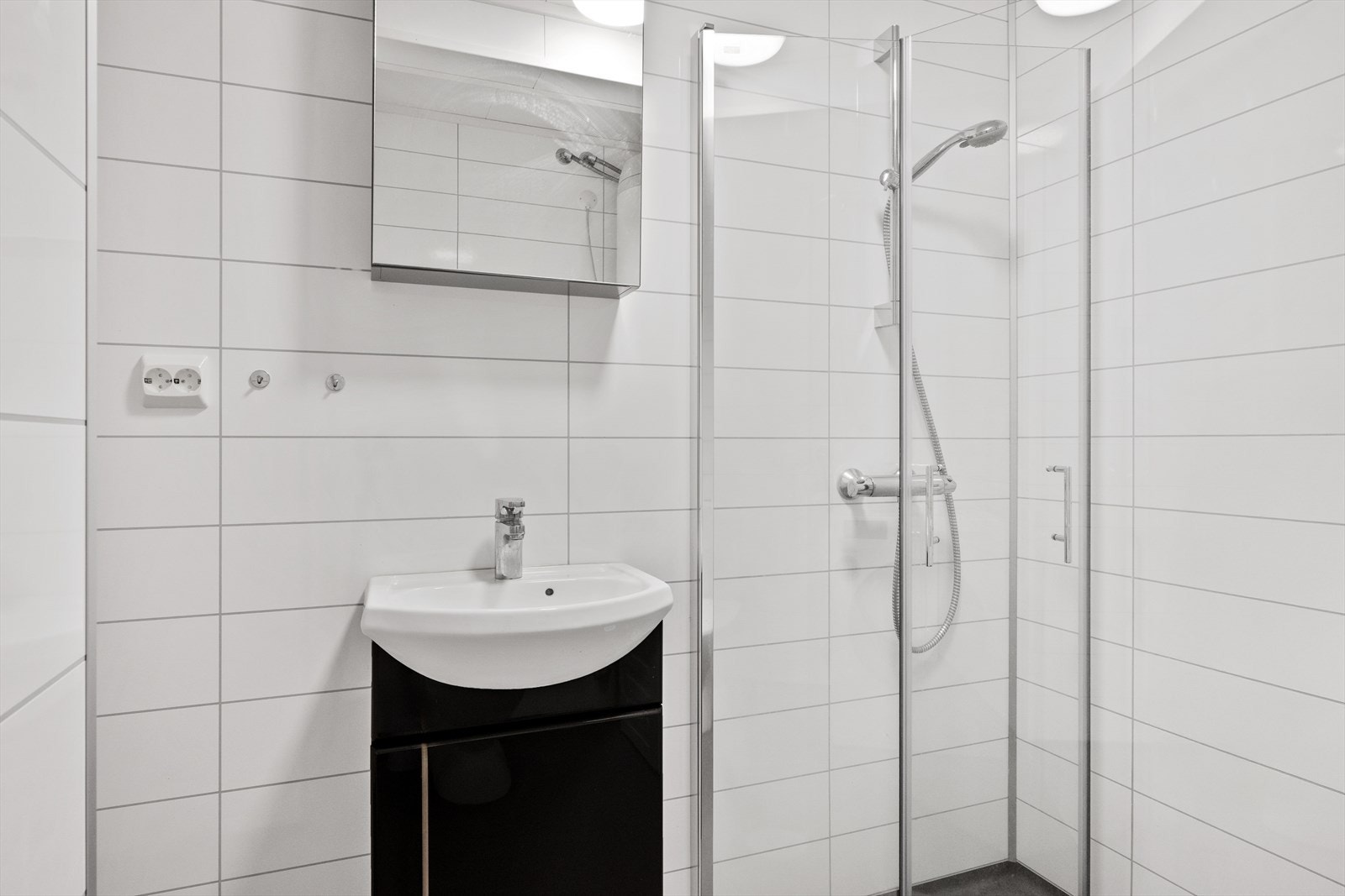 Badet er utstyrt med servantskap, toalett, dusjhjørne med glassdører, opplegg for vaskemaskin og varmtvannsbereder. Galleribilde