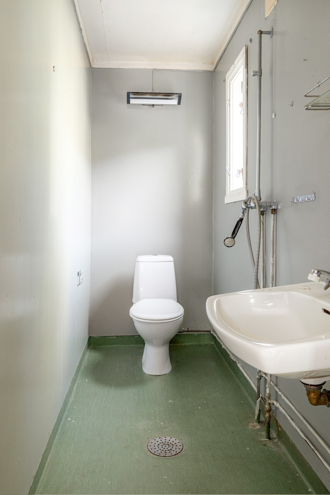 Enkelt bad med vinylbelegg på gulv og malte plater på vegger. Her er det toalett, vask og åpen dusj. Varmtvannstank fra 2010 på 198 liter er plassert på gulv i kjeller. Galleribilde