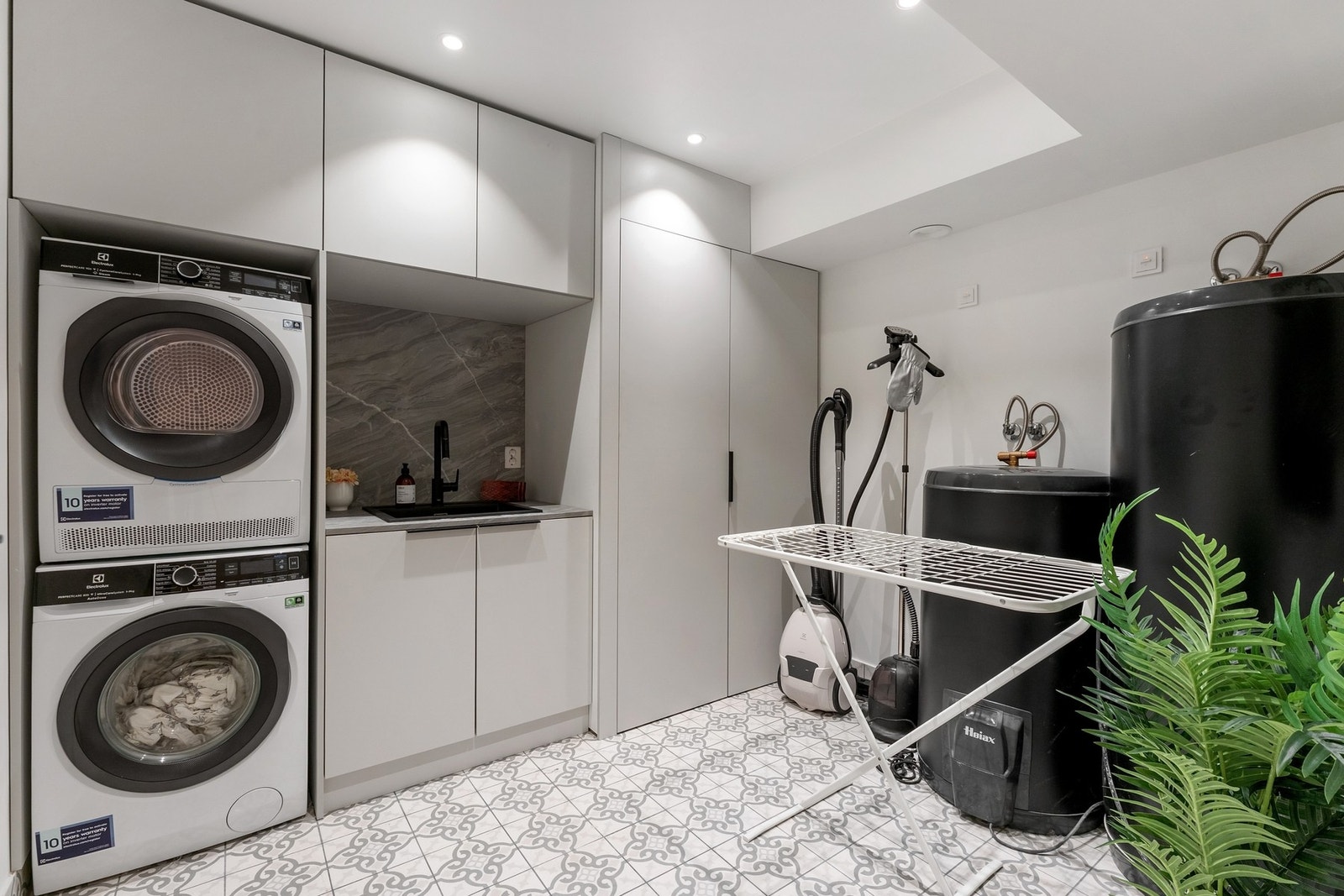 Romslig vaskerom med tilpassede skap og plass til vaskemaskin og tørketrommel