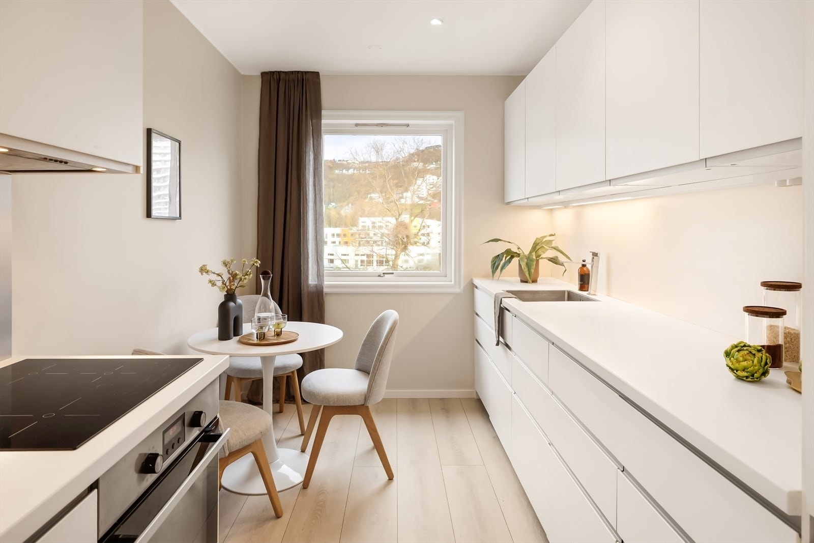 Lyst og velholdt kjøkken fra 2015 på 8,8 m², med hvite glatte fronter, benkeplate i laminat og integrerte hvitevarer. Galleribilde