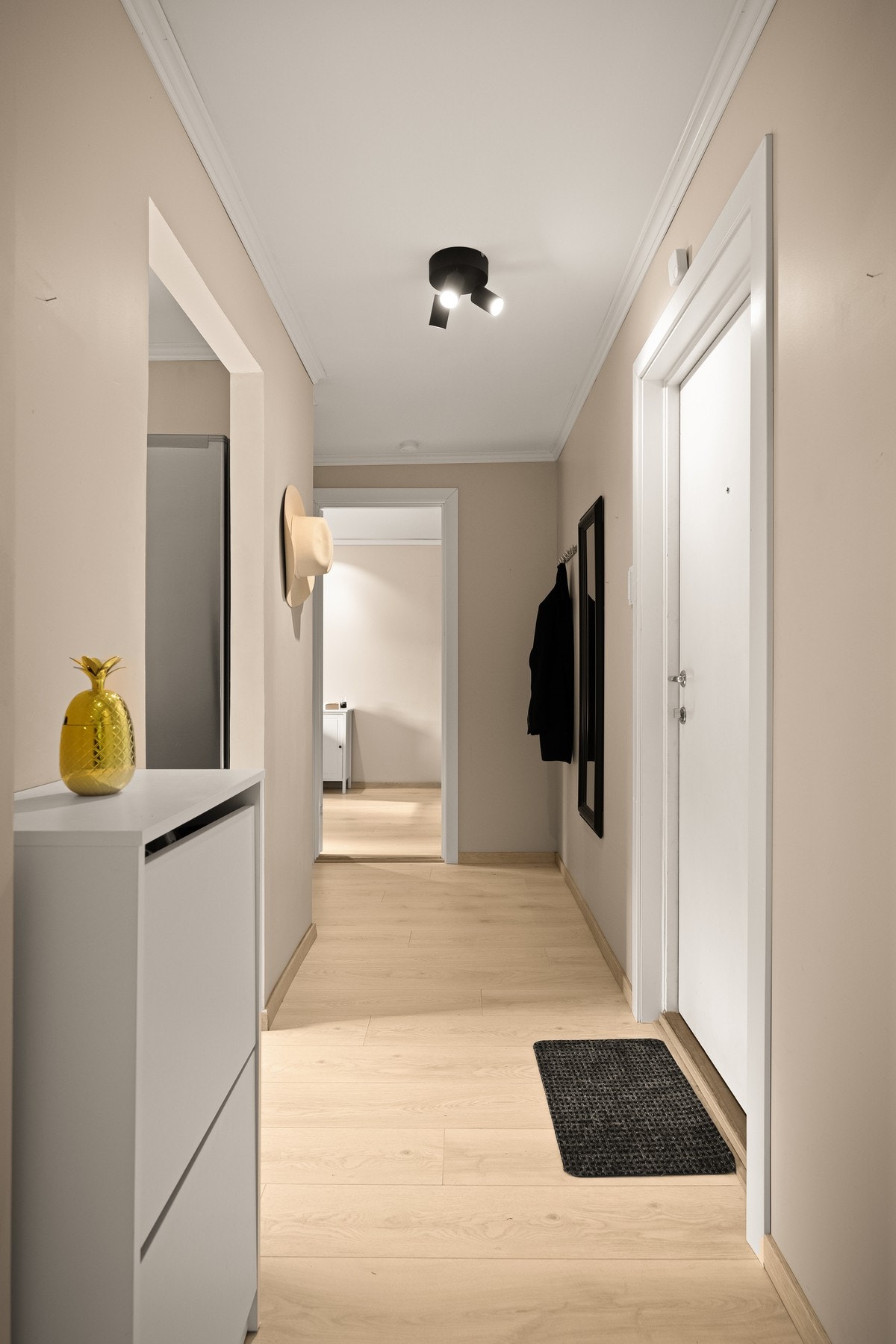 Lys og innbydende gang med laminat på gulv og plass til oppbevaring. Galleribilde