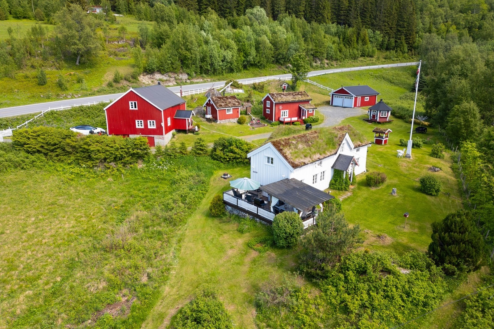 Svært pent opparbeidet tomt med tilnærmet flat plen, prydbusker, blomster og interne stier av naturstein. Galleribilde