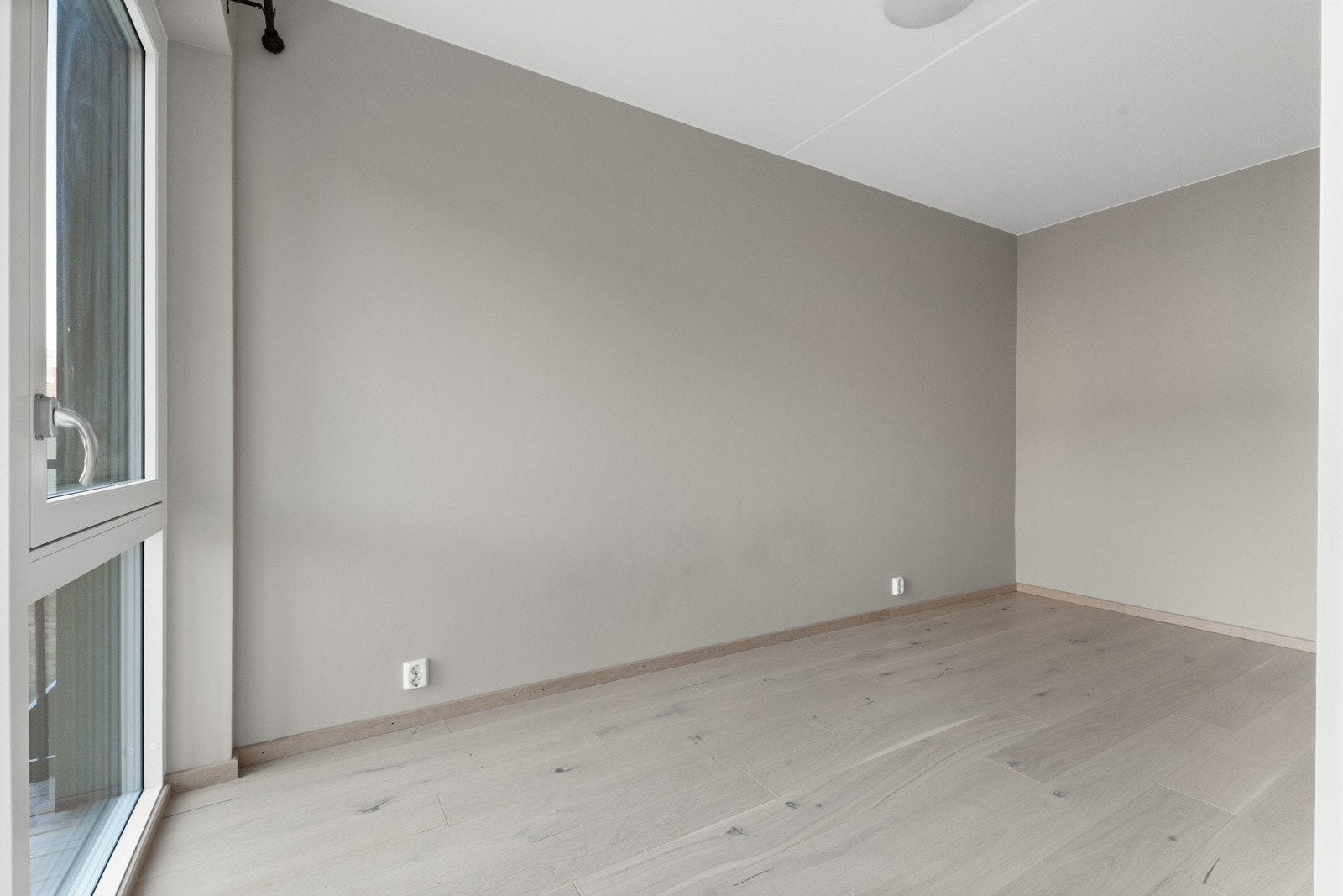 Soverommet har lysmalte veggflater, hvitpigmentert parkett på gulv og store vindusflater Galleribilde