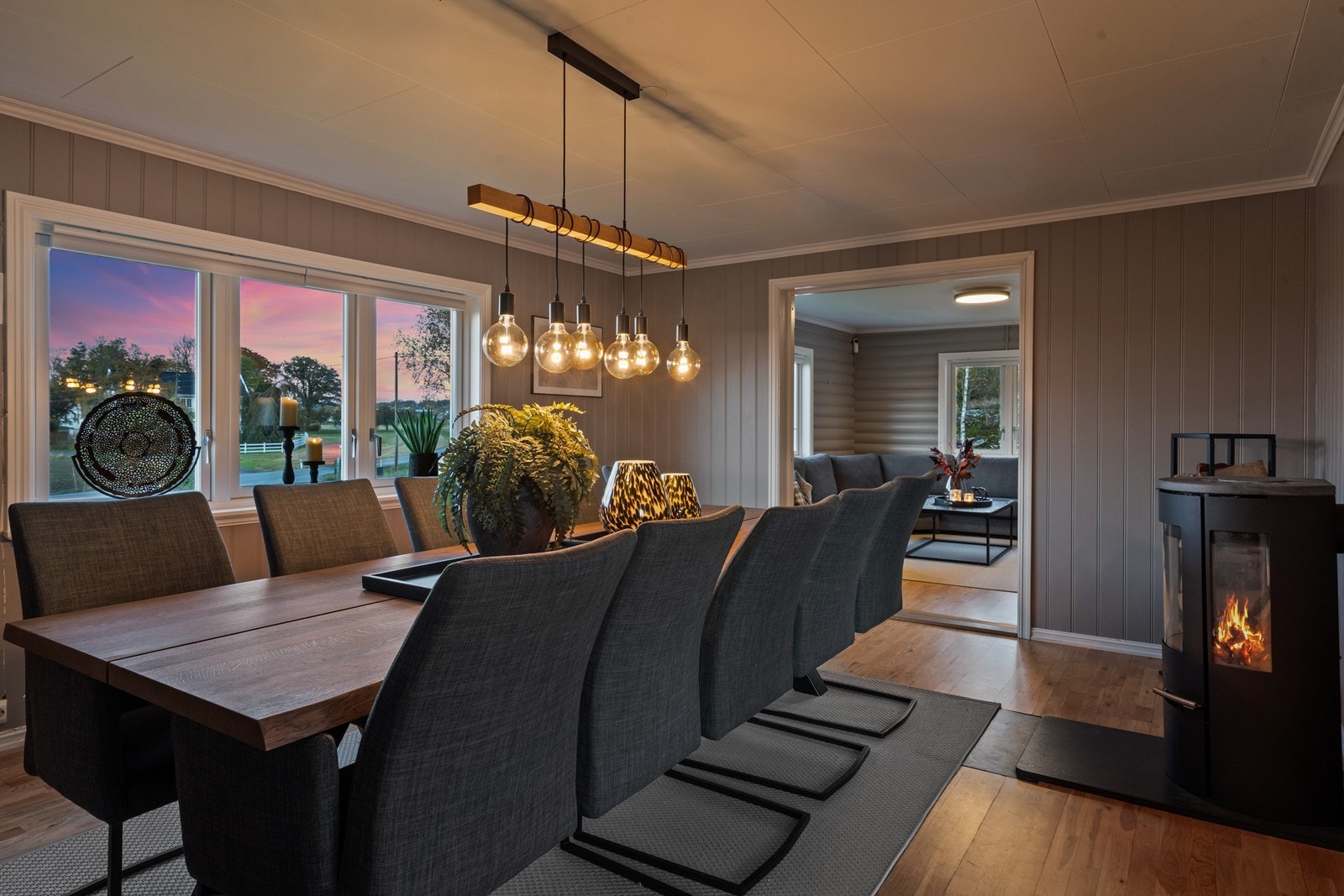 Luftig og åpen løsning mellom kjøkken og spisestue med god varme fra peisovnen en kald høstdag Galleribilde