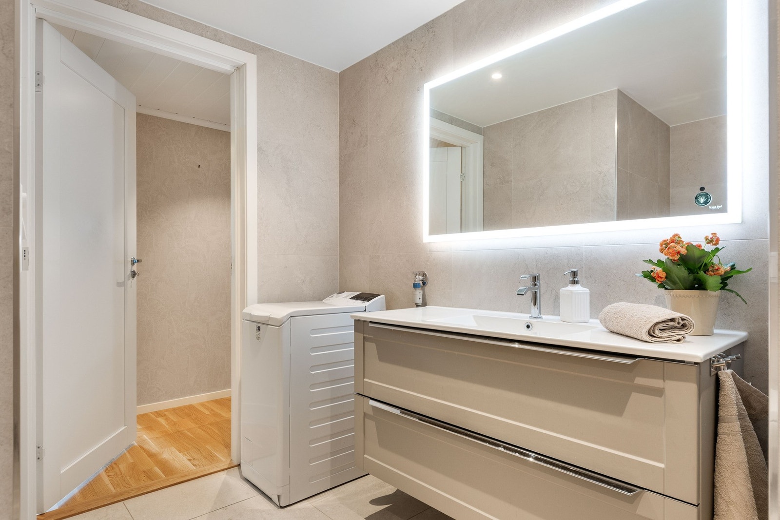 Delikat baderom med lyse fliser på gulv og vegg. Pen innredning med nedfelt servant. Galleribilde