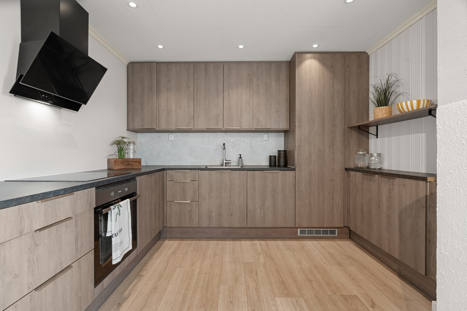 Innbydende og nyere kjøkken med slette fronter som gir et klassisk og tidløst utseende. Innredning ble byttet i 2023. Det er godt med skap- og benkeplass, noe som gjør det enkelt å holde orden og ha alt du trenger innen rekkevidde. Galleribilde