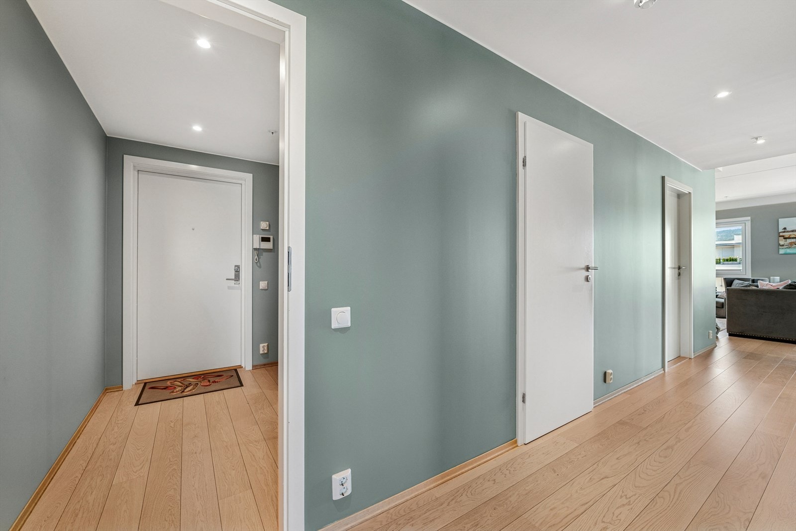 Gangen er gjennomført med lekker parkett på gulvet, samt lyse og behagelige farger på vegger og tak. Det er montert praktisk skyvedørsgarderobe med speilfront. Galleribilde