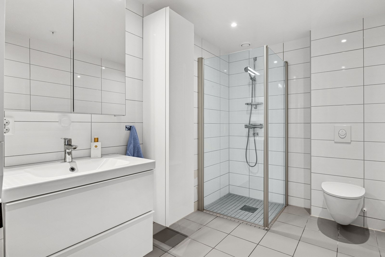Badet er innredet med en praktisk og stilfull innredning med god oppbevaringsplass, montert skap på vegg, heldekkende servant, belyst speilskap for oppbevaring og vegghengt toalett. Det er termostatstyrt elektriske varmekabler i gulvet. Galleribilde