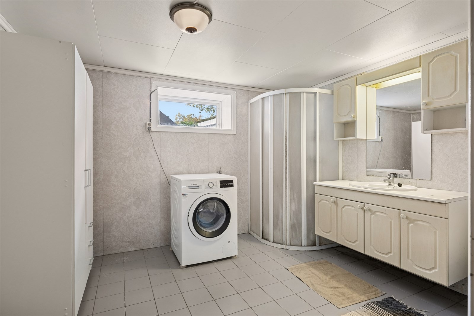 Rommet er innredet med servant og underskap, klosett, dusjhjørne og opplegg for vaskemaskin. Galleribilde