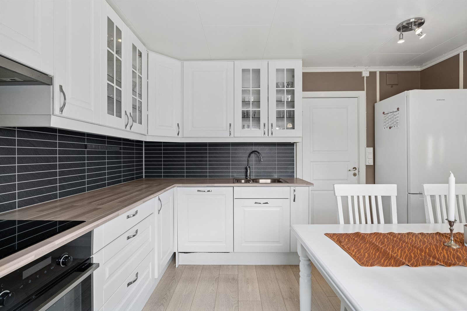 Kjøkkeninnredningen har klassiske, hvite fronter med både overskap, som gir rikelig med oppbevaringsplass. Galleribilde