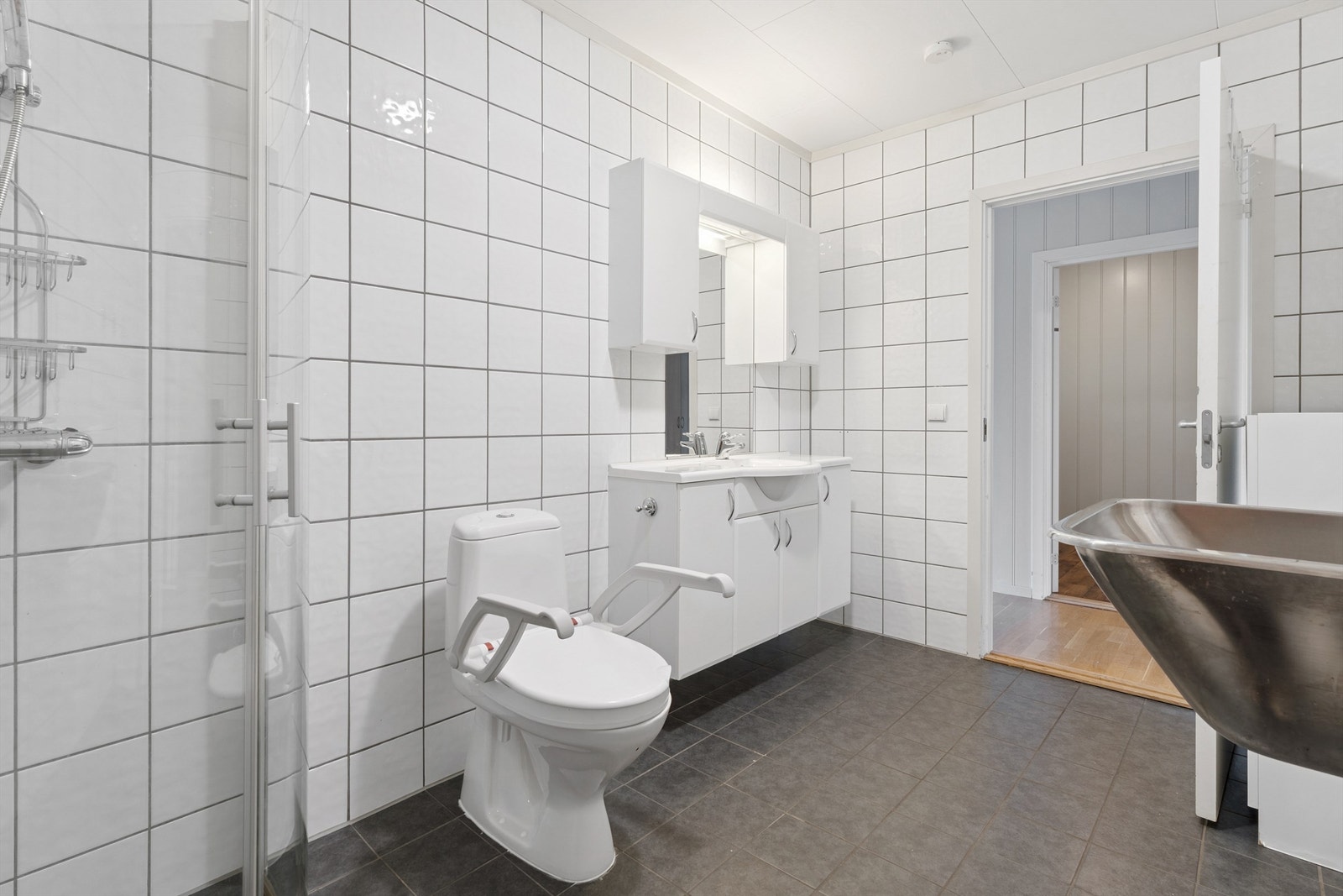 Rommet inneholder dusjhjørne, toalett, baderomsinnredning, utslagsvask og opplegg for vaskemaskin. Galleribilde