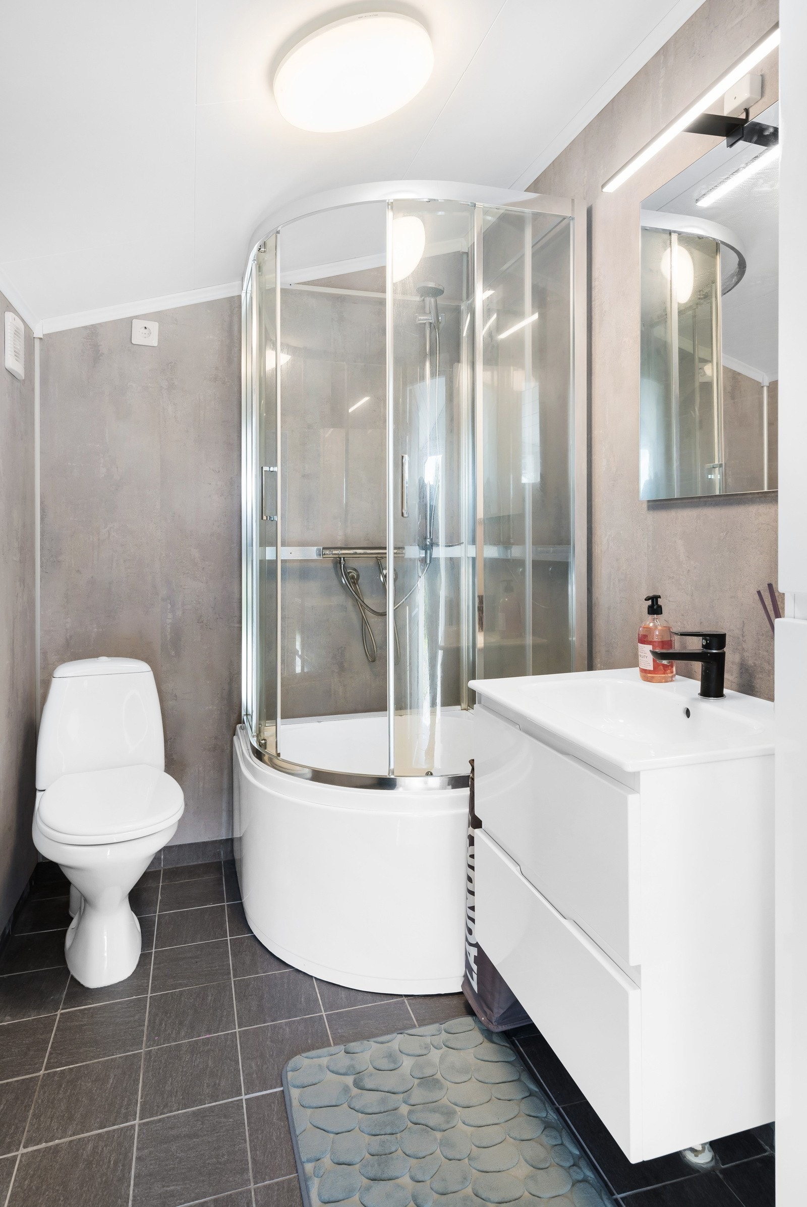 Praktisk bad med dusjkabinett, wc, servantinnredning og lyse, tidløse materialvalg Galleribilde