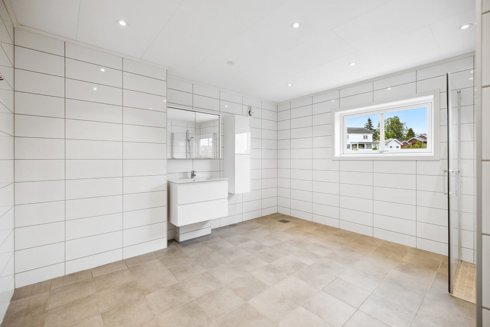 Badet har en stilig innredning med heldekkende servant på hvit skuffeseksjon, sideskap og speilskap med belysning. Galleribilde