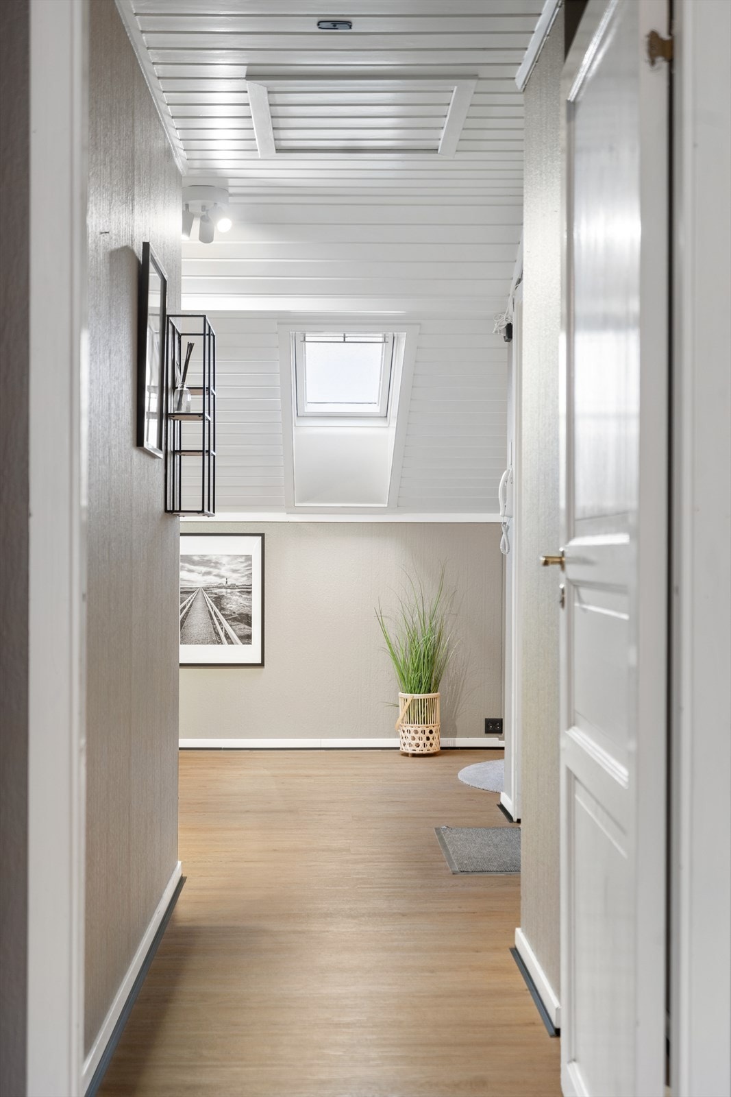 Fra gangen ser man inn mot soverommet, der takvinduet slipper inn naturlig lys og skaper en lun og harmonisk atmosfære Galleribilde