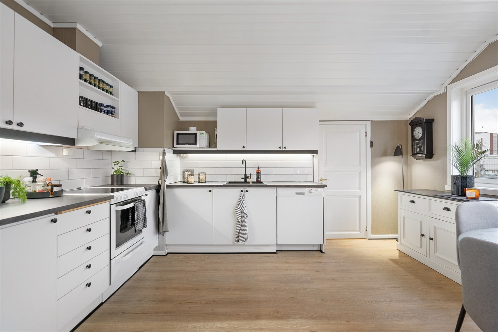 Lyst og innbydende kjøkken med moderne uttrykk og rene linjer. Her får du god benkeplass, praktisk planløsning og integrert belysning som gir et lunt arbeidslys Galleribilde