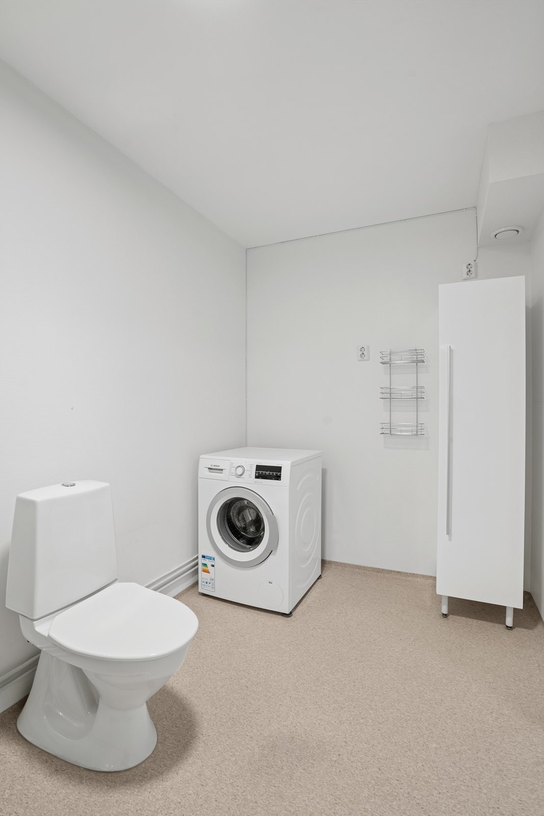 Det er opplegg for vaskemaskin. Badet har plastsluk, og vinylbelegg er synlig som tettesjikt. Ventilasjonen består av mekanisk avtrekk. Galleribilde