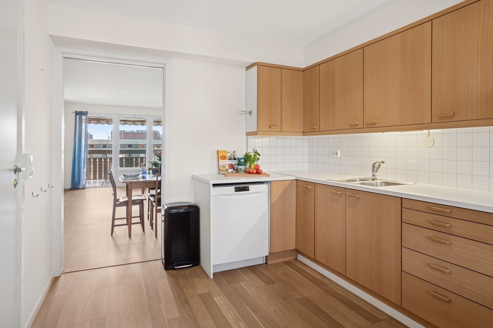 Kjøkkeninnredning med glatte fronter og laminat benkeplate med nedfelt vaskekum. Det er belysning og splashboard over benkeplaten, samt takhøye overskap. Galleribilde