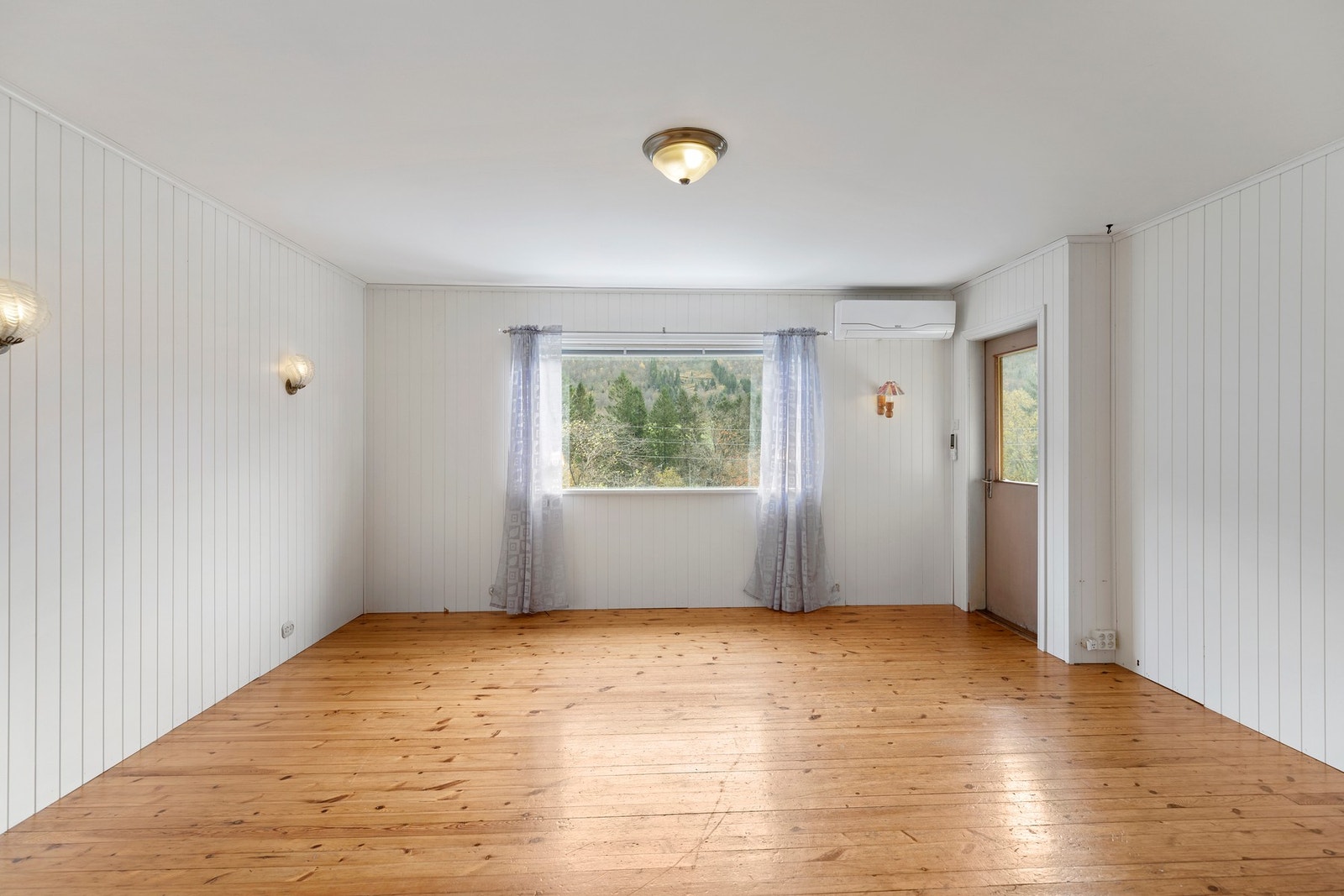 Rommet har trebord på gulv og mdf-plater på vegger. Galleribilde