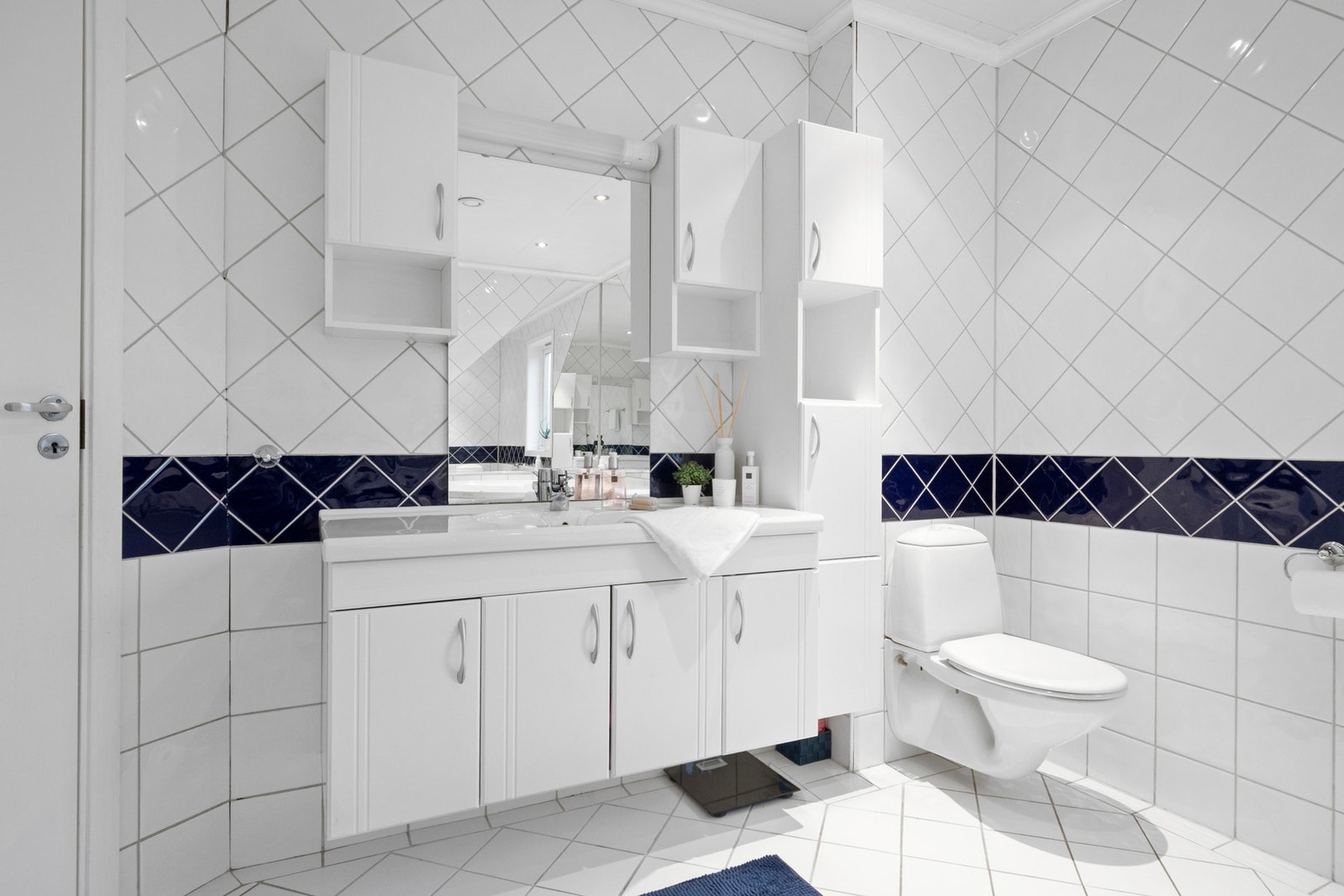 Badet oppe har hvite fliser med innslag av mørkeblått på veggene Galleribilde