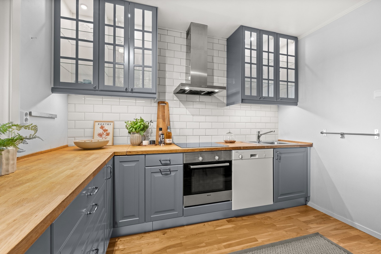 IKEA kjøkkeninnredning med profilerte fronter. Overskap er vitrineskap med glasshyller og belysning. Benkeplate i eik. Galleribilde