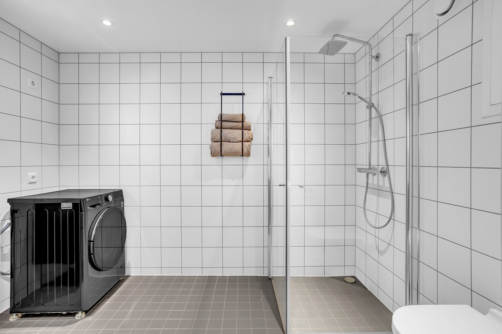 Badet har sort servantskap, belyst speil, toalett, dusjhjørne og opplegg for vaskemaskin/tørketrommel. Galleribilde