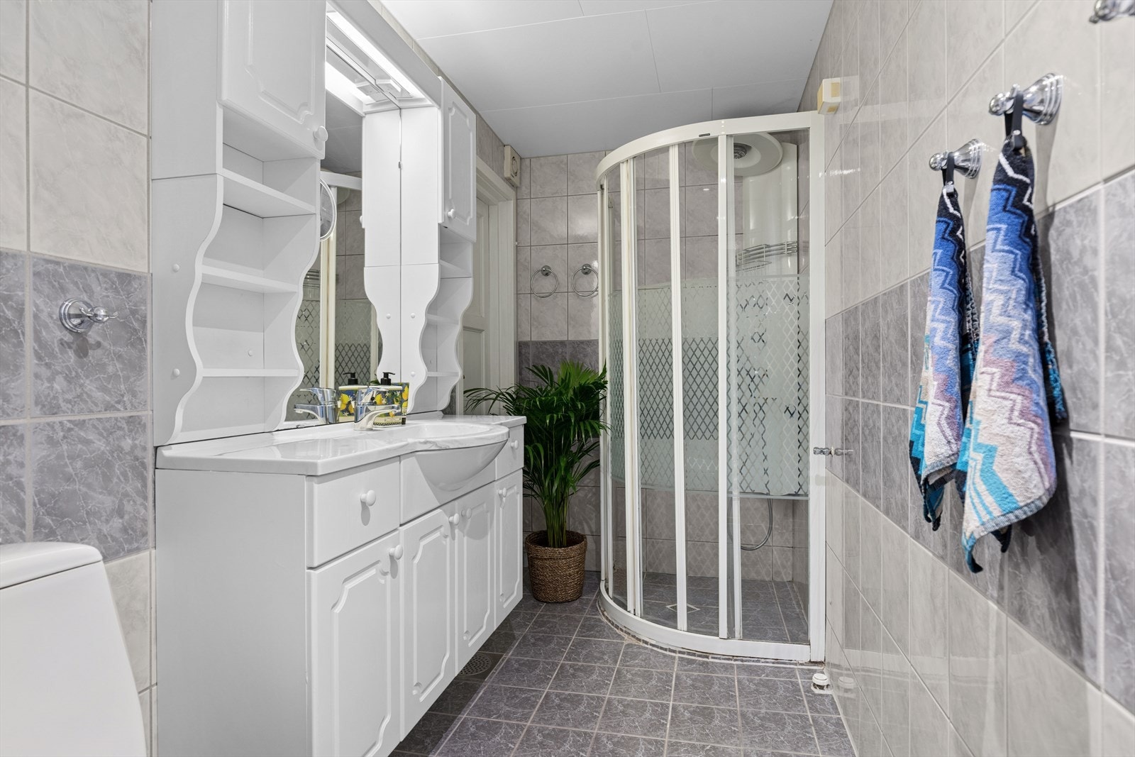 Badet er innredet med dusjhjørne, servantseksjon, overskap med speil/lys og gulvmontert wc. Galleribilde