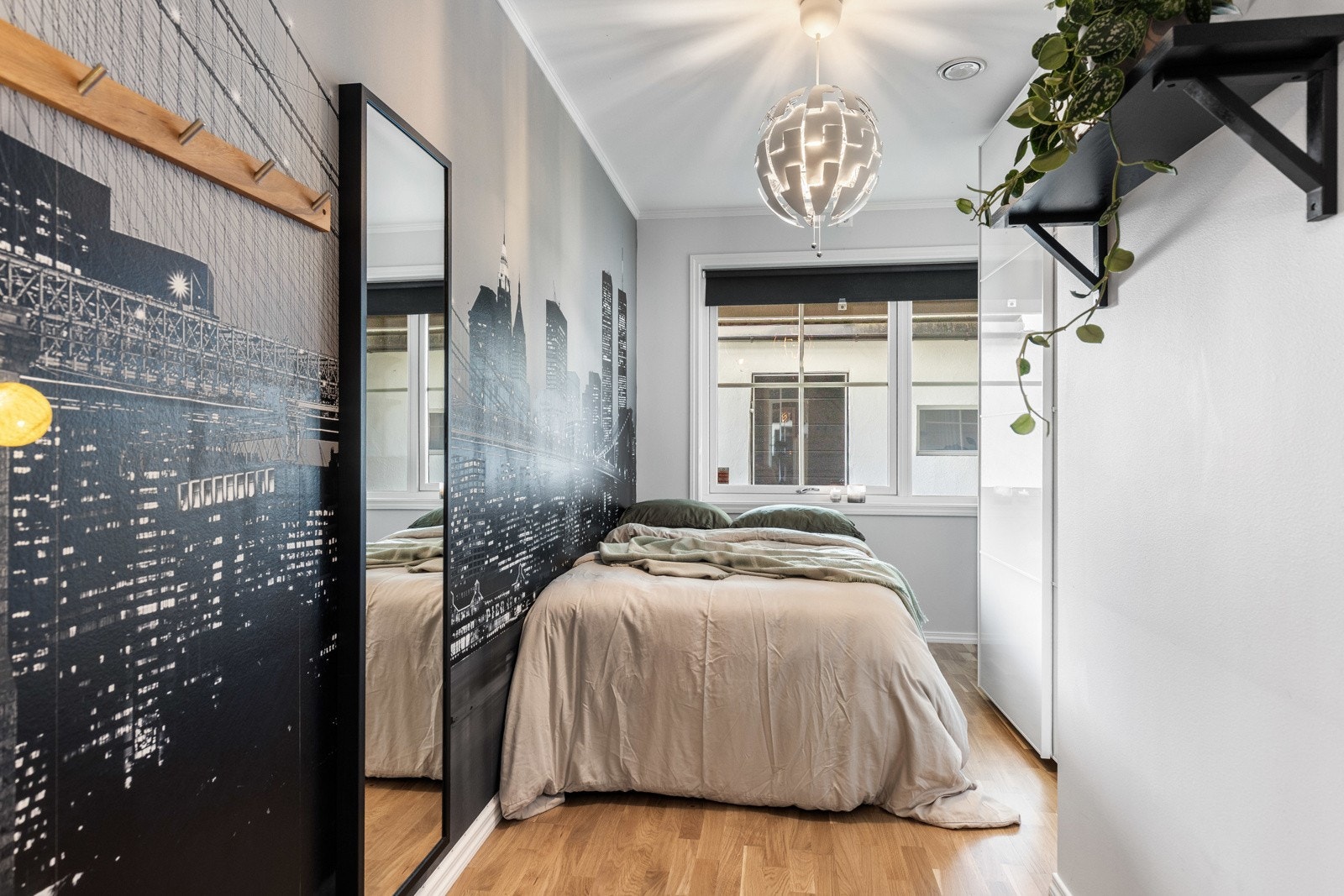 Praktisk soverom med store vindusflater, garderobeløsning og en kreativ fondvegg som setter særpreg på rommet. Galleribilde