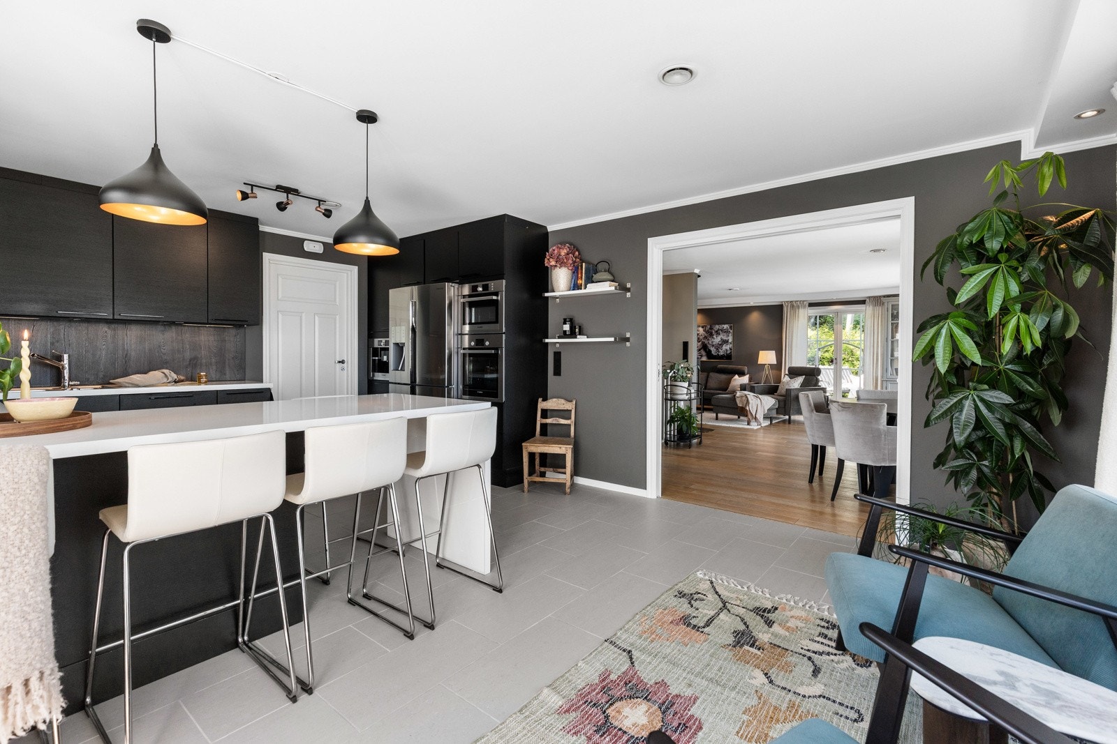 Stilrent kjøkken med mørke fronter, store arbeidsflater og praktisk kjøkkenøy med sitteplasser. Et naturlig samlingspunkt i hjemmet. Galleribilde