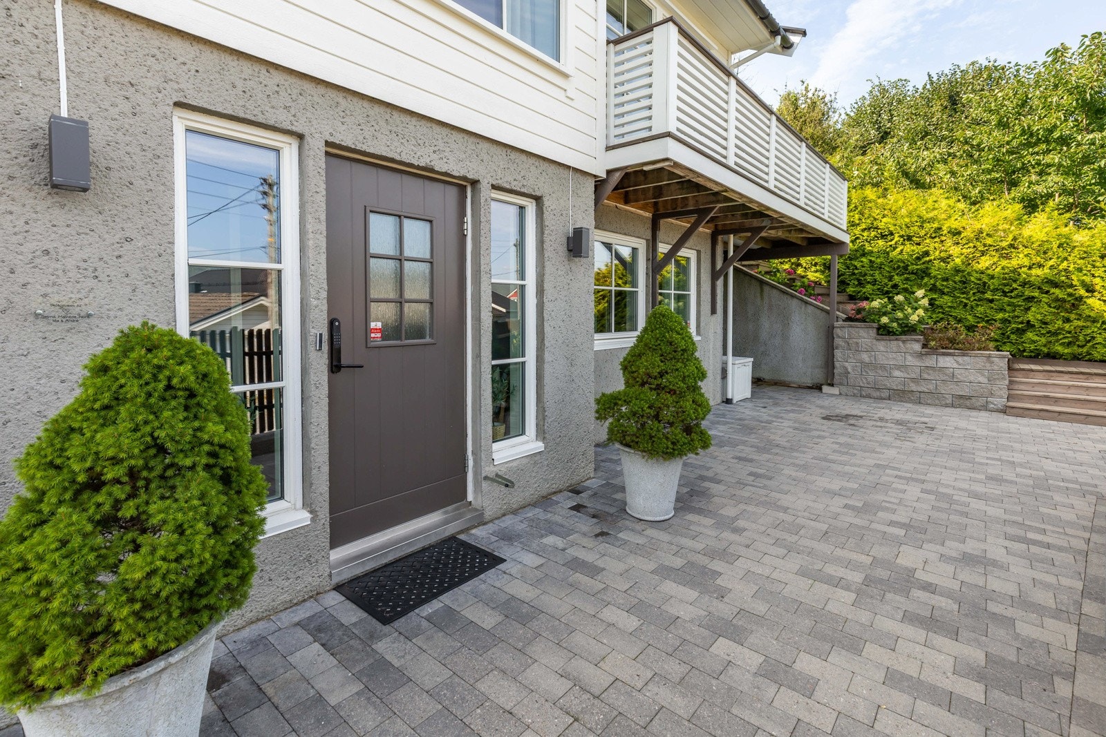 Inngangspartiet er pent opparbeidet med belegningsstein, beplantning og en praktisk adkomst til boligen. Galleribilde