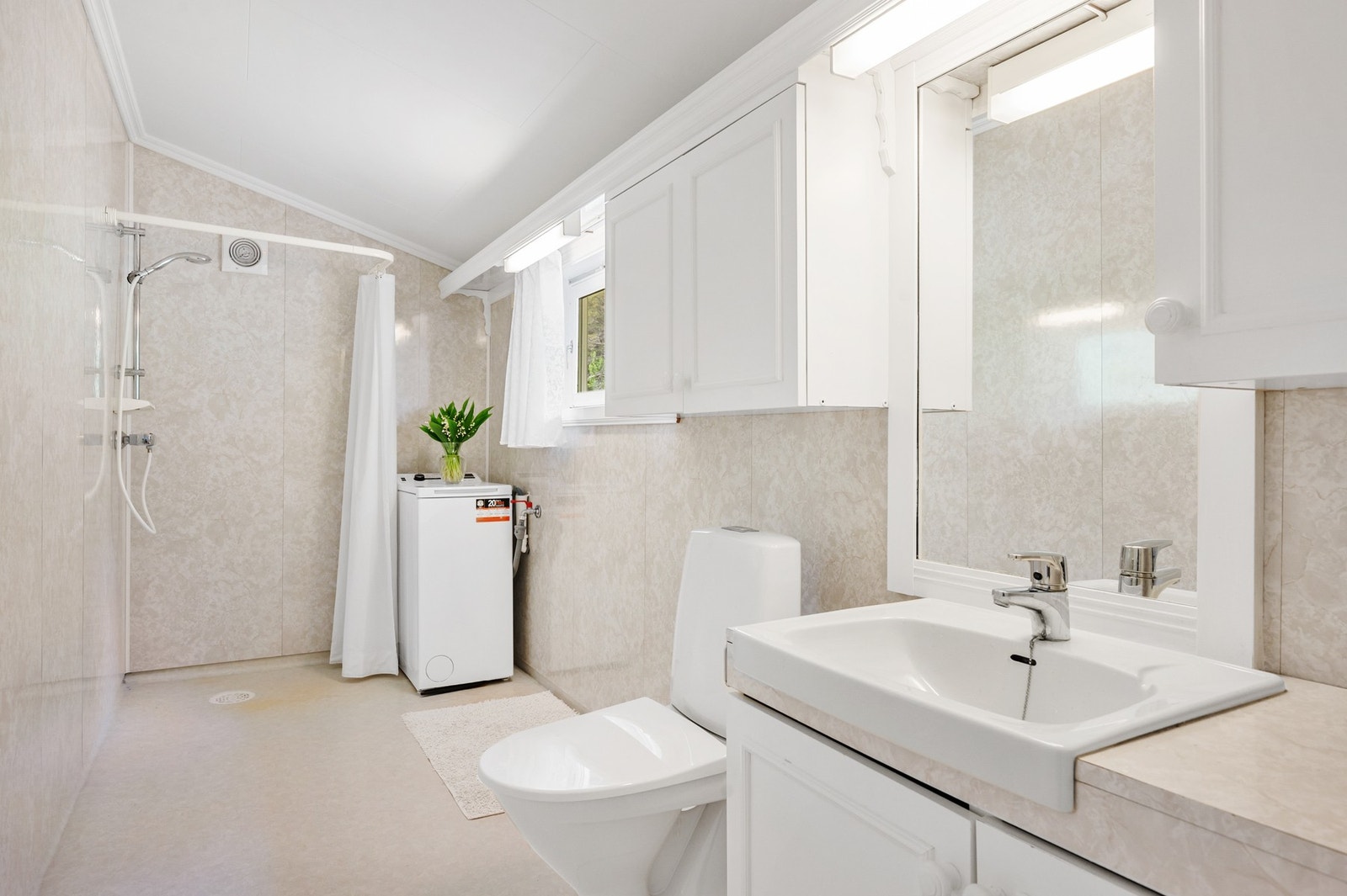 Baderom/vaskerom med toalett, servant, dusj-hjørne og opplegg for vaskemaskin. Galleribilde