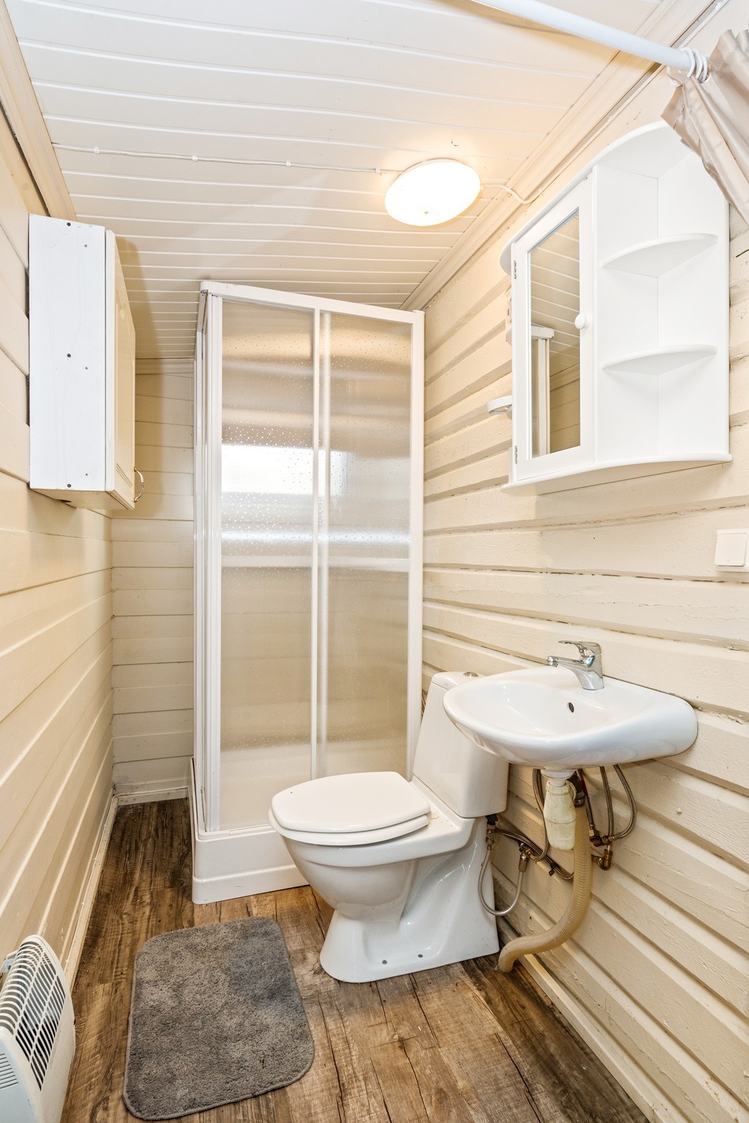 Bad med ukjent høy alder. Rommet har servant, gulvfestet toalett og dusjkabinett. Galleribilde