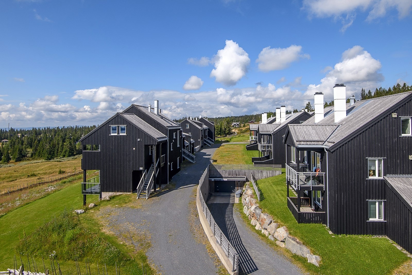 Bilde fra adkomsten til sameiet. Nedkjøring til felles garasjeanlegg med boder. Det er enkel adkomst fra garasjen og inn til leiligheten. Trapp ned fra internområdet. Galleribilde