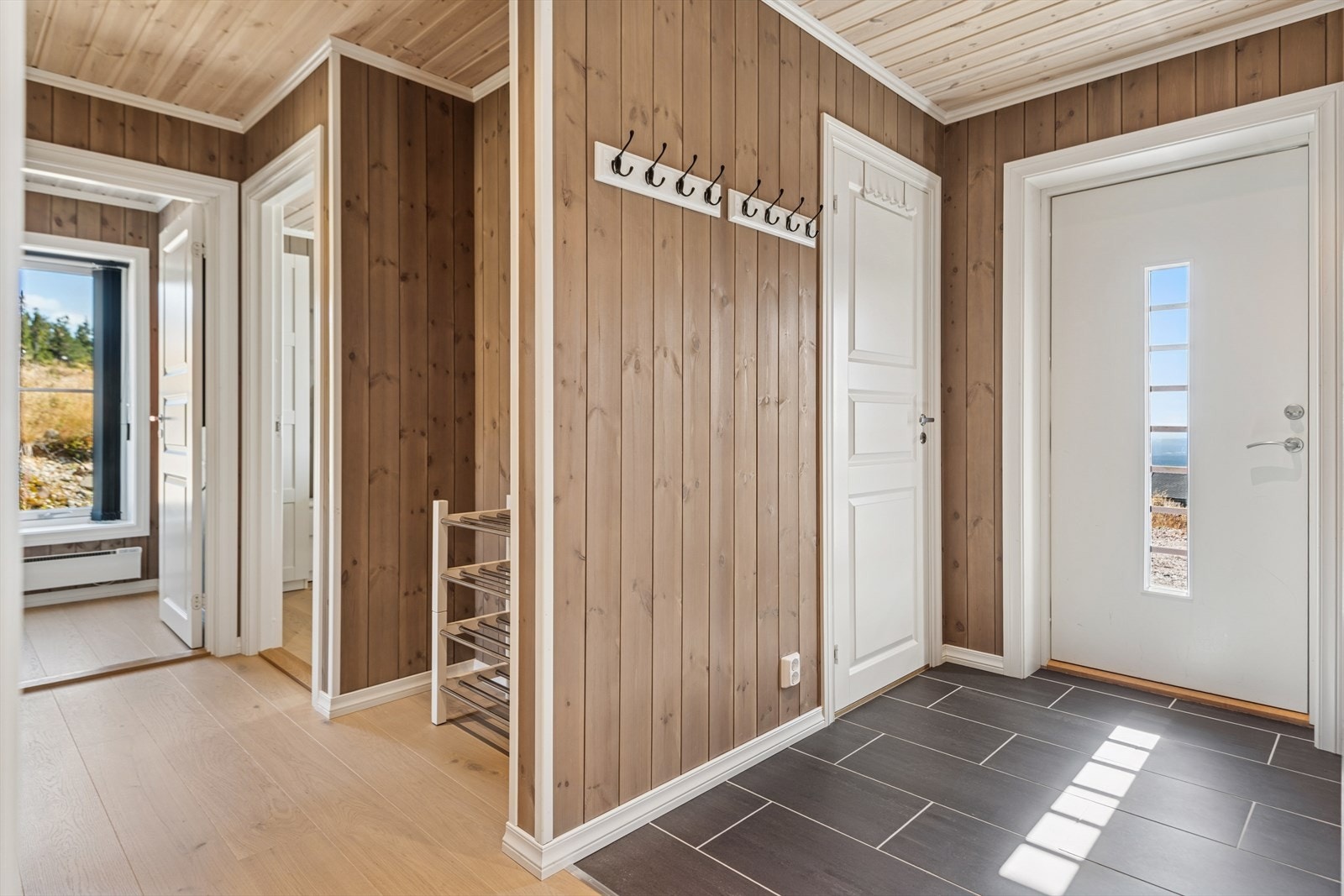 God plass til å henge fra seg klær og sko. Dør inn til praktisk bod med oppbevaringsplass til skiutstyr, ved og annet utstyr. Galleribilde