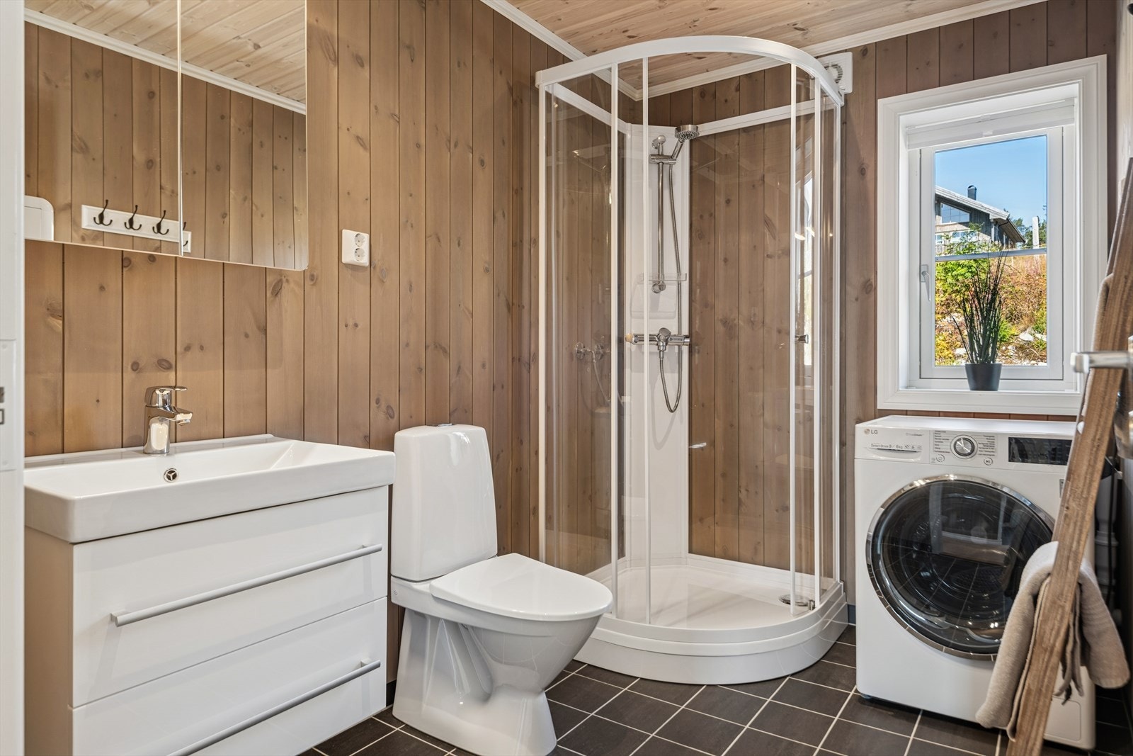 Pent bad med fliser og varme på gulv. Dusjkabinett, gulvmontert toalett og servant med underskap og speilskap. Galleribilde